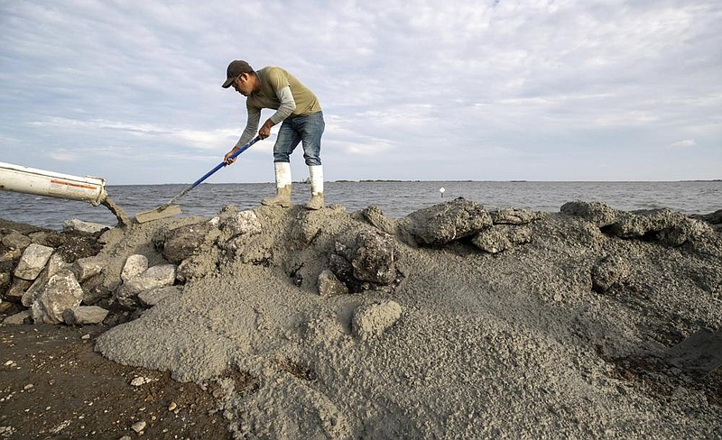 Raul Estrada, an employee of Terrebonne Parish in south Louisiana, stabilizes a coastal rock wall with cement Wednesday near Isle de Jean Charles, La. Hurricane Delta is expected to make landfall south of Morgan City, La., on Friday. Because of the forecast, the SEC moved Saturday’s game between LSU and Missouri from Baton Rouge to Columbia. Mo.
(AP/The Advocate/David Grunfeld)