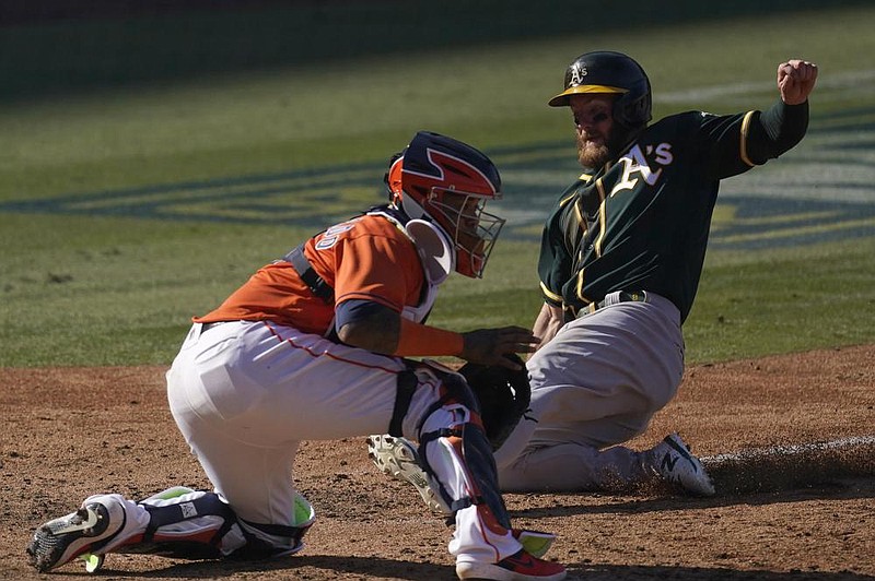 Robbie Grossman (right) of the Oakland Athletics slides safely into home in front of Houston Astros catcher Martin Maldonado during the eighth inning of the Athletics’ victory Wednesday in Game 3 of their American League division series at Los Angeles.
(AP/Ashley Landis)