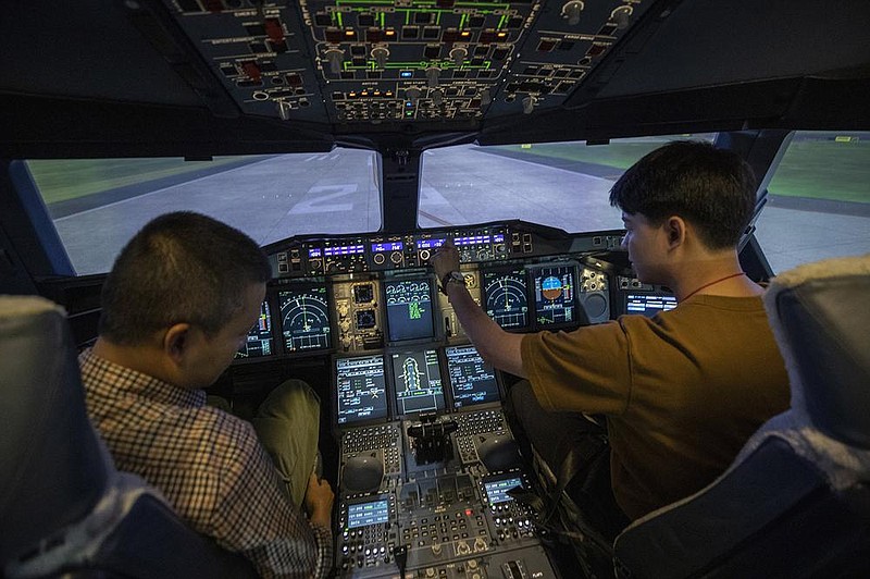 Customers sit in an Airbus A380 flight simulator Saturday during a flight experience at the Thai Airways head office in Bangkok. The airline is selling time on its flight simulators to wannabe pilots.
(AP/Sakchai Lalit)