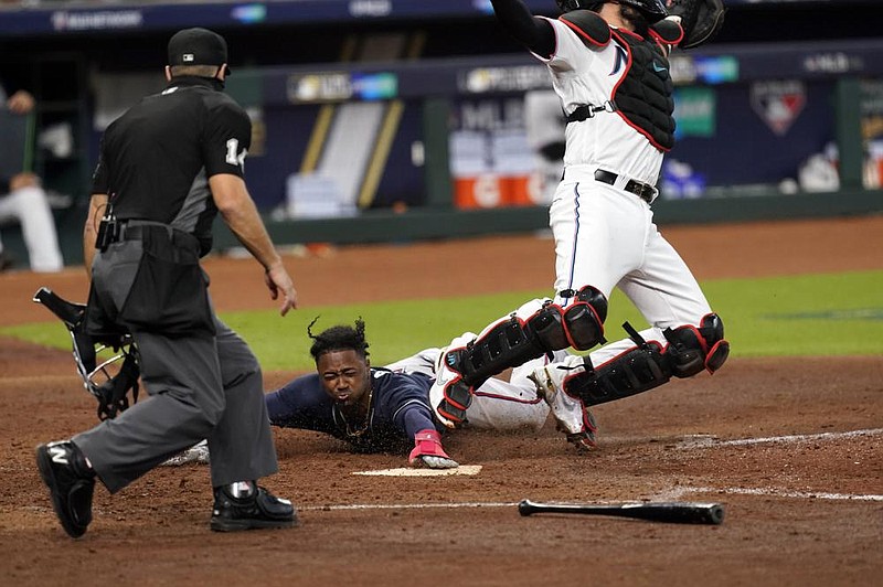 Atlanta second baseman Ozzie Albies slides into home plate Thursday to score a run on a hit by Dansby Swanson during the fifth inning of the Braves’ 7-0 victory over the Miami Marlins in Game 3 of their National League division series in Houston.
(AP/Eric Gay)