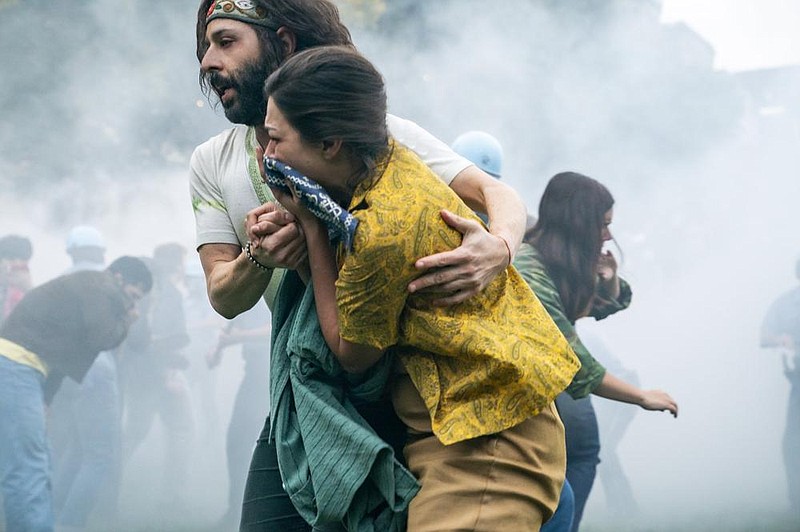 Yippie Jerry Rubin (Jeremy Strong) and his associate Bernadine (Alice Kremelberg) muddle through a tear gas attack in “The Trial of the Chicago 7” (2020).