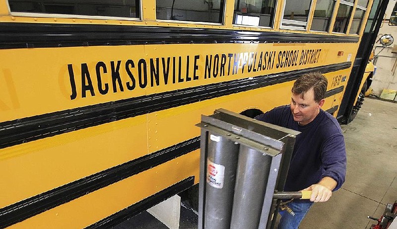 Diesel mechanic Jesse Nix positions a lift while working on a Jacksonville/North Pulaski School District bus in this June 2016 file photo.