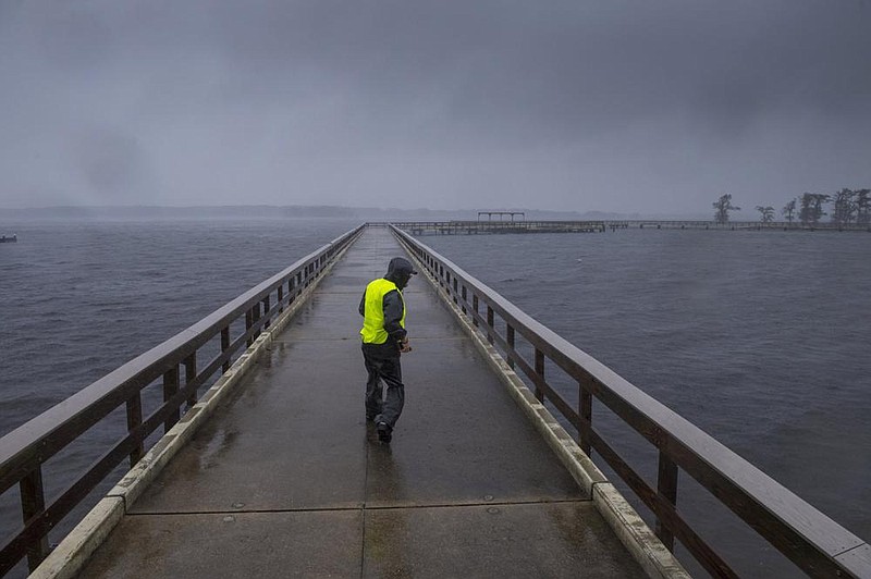 Storm chaser Shaun Piegdon walks along a pier Friday at Lake Arthur as Hurricane Delta’s outer bands move into Louisiana. More photos at arkansasonline.com/1010delta/.
(AP/The Advocate/Chris Granger)