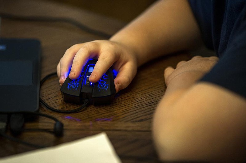 Ethan Beasley, 9, uses his gaming mouse as he and his brother, Eli, attend school from their home in Sherwood on Friday, Oct. 2, 2020. 

(Arkansas Democrat-Gazette / Stephen Swofford)