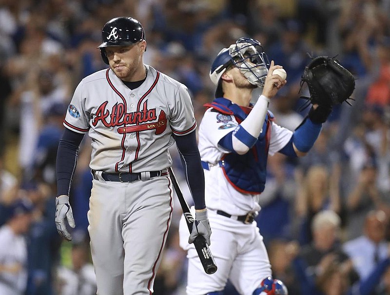 FILE - In this Oct. 5, 2018, file photo, Atlanta Braves' Freddie Freeman, left, walks away after striking out as Los Angeles Dodgers catcher Yasmani Grandal celebrates the Dodgers' 3-0 win in Game 2 of a baseball National League Division Series in Los Angeles. Those Baby Braves that faced the Dodgers in the playoffs two years ago have grown up a little bit, and have even won a couple of postseason series. (Curtis Compton/Atlanta Journal Constitution via AP, File)