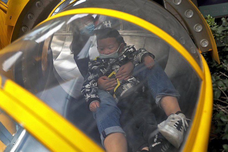 A masked woman and a child enjoy a slide Sunday at a shopping mall in Beijing. (AP/Andy Wong) 