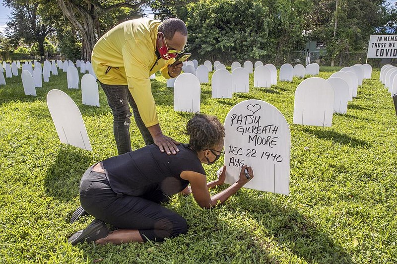 Rachel Moore honors her mother, Patsy Gilreath Moore, as Le- roy Lee reaches out to comfort her Wednesday at Simonhoff Park in the Liberty City neighborhood of Miami. Five hundred coroplast tombstones are being displayed to represent people who have died from the coronavirus. 
(AP/Miami Herald/Al Diaz) 