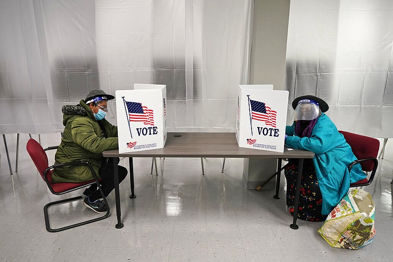 FILE - In this Oct. 6, 2020, file photo two voters fill out ballots during early voting at the Cuyahoga County Board of Elections in Cleveland. A surge in coronavirus cases is hitting key presidential battleground states a little more than two weeks before Election Day, raising concerns that voting could be thrown into chaos despite months of preparation and planning by election officials and voters. (AP Photo/Tony Dejak, File)

