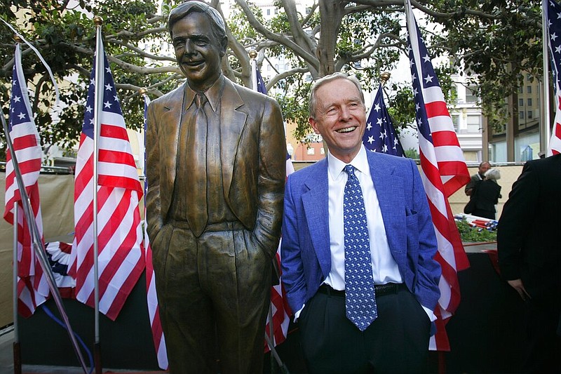 Former California Gov. Pete Wilson imitates the pose of a statue dedicated in his honor at Horton Plaza in San Diego in this Aug. 25, 2007, file photo. The statue was removed from the park after critics said the governor supported laws and policies that hurt immigrants and the gay and transgender communities, the San Diego Union-Tribune reported Thursday, Oct. 16, 2020.