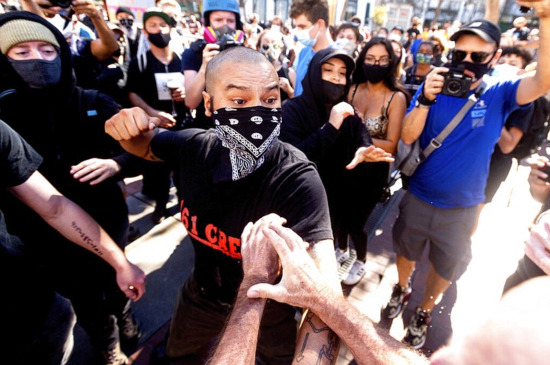 A counterprotester, who declined to give his name, raises his fist to a conservative free-speech rally organizer in San Francisco on Saturday, Oct. 17, 2020. About a dozen pro-Trump demonstrators were met by several hundred counterprotesters. story.lead_photo.caption