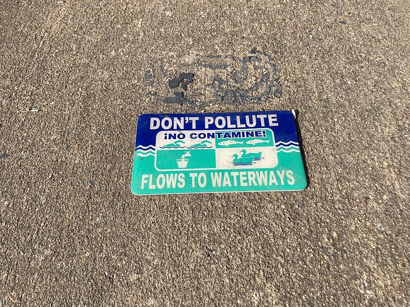 Small signs like this one remind the public that anything that goes down an outside drain flows directly into the waterway and can pollute streams and rivers. (Pine BluffCommercial/Byron Tate)