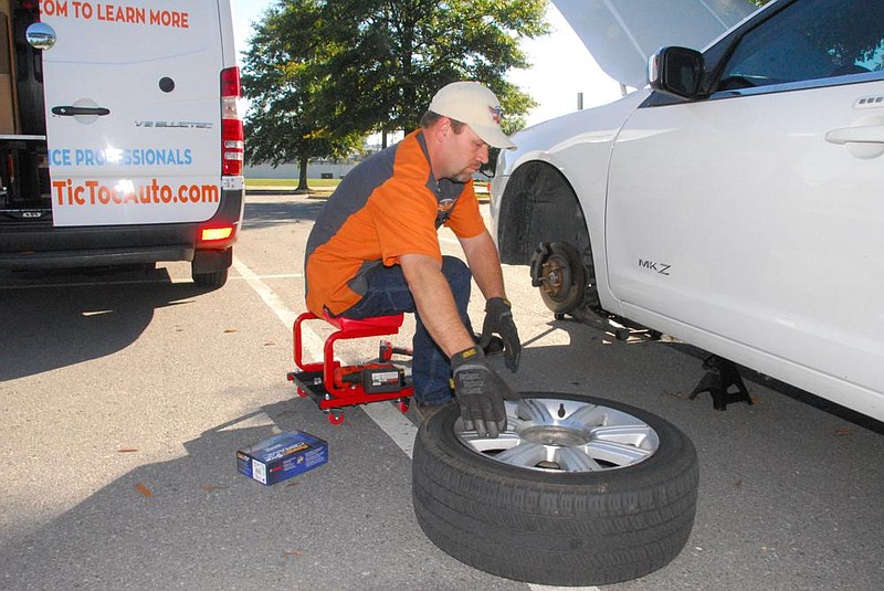 Nathan Moore, lead technician for Tic Toc Auto, gets ready to install a tire after completing brake job  for customer in a parking lot next to a downtown North Little Rock apartment complex.
(Arkansas Democrat-Gazette/Noel Oman)