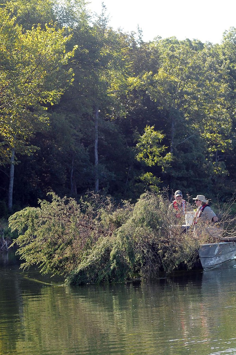 Jon Stein (left) and Kevin Hopkins, fisheries biologists with the Arkansas Game and Fish Commission, transport cedar trees cut from Deer Island and Bear Island at Beaver Lake—created by the construction of Beaver Dam on the White River in Carroll County in 1955—to sub- merge them in the lake for fish habitat. (NWA Democrat-Gazette/Flip Putthoff) 