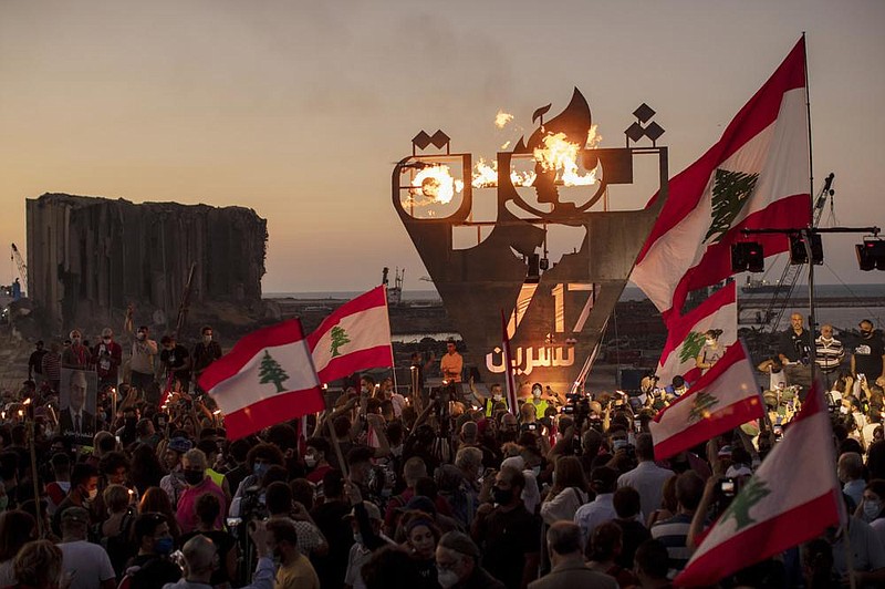 Anti-government protesters wave Lebanese flags Saturday as they light a flame over a metal statue that reads, “Oct. 17, Revolution,” next to the site of the Aug. 4 explosion in the seaport of Beirut.
(AP/Hassan Ammar)