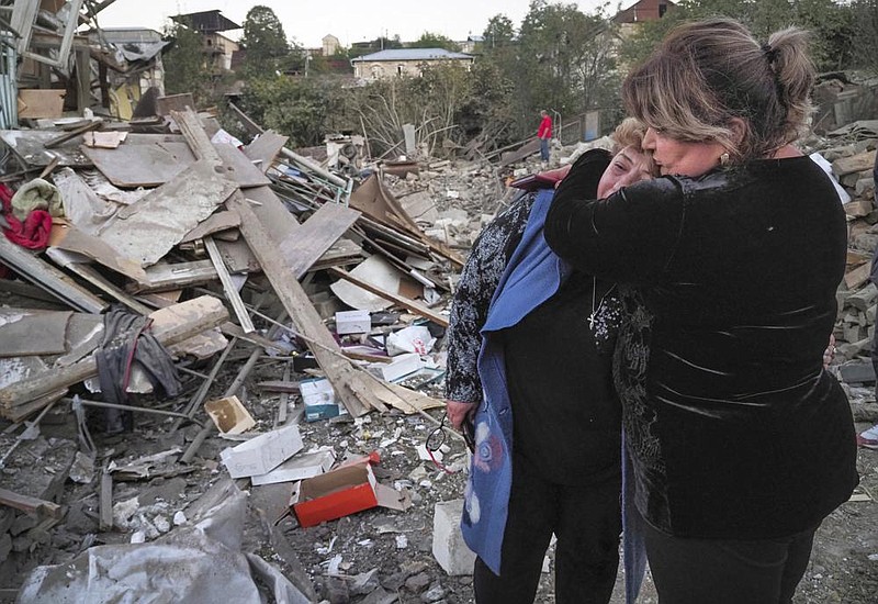 Lida Sarksyan (left) is comforted by a neighbor Saturday near the wreckage of her home, which was destroyed by Azerbaijani artillery fire in Stepanakert in the Nagorno-Karabakh separatist region. More photos at arkansasonline.com/1018nagorno/.
(AP)