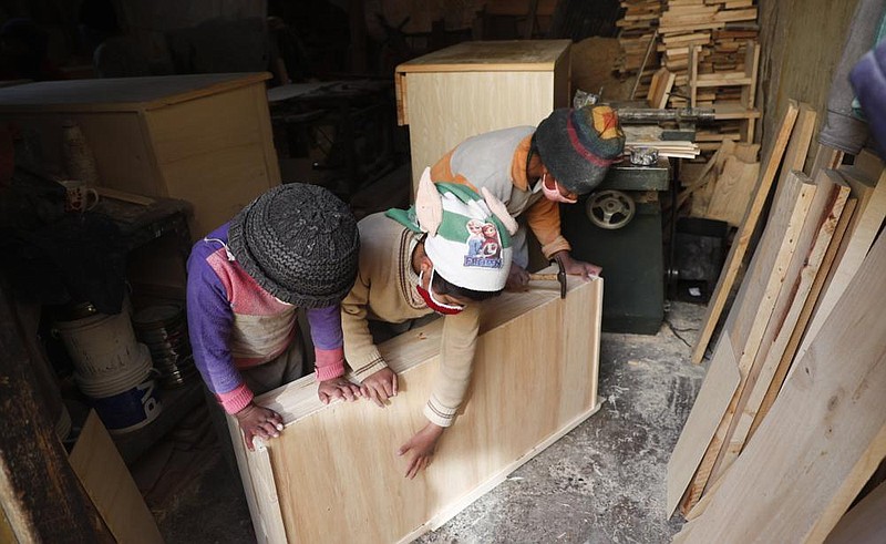 Three of the Delgado children, from right, Yuri, 11, Wendi, 9, and Alison, 8, make a drawer in the family carpentry workshop in El Alto, Bolivia, in early September.
(AP/Juan Karita)
