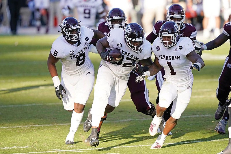 Texas A&M defensive lineman Jayden Peevy (middle) runs with the ball after recovering a fumble Saturday while escorted down the field by teammates DeMarvin Leal (8) and Buddy Johnson during the second half of the No. 11 Aggies’ 28-14 victory over Mississippi State on Saturday in Starkville, Miss. Peevy did not score on the play.
(AP/Rogelio V. Solis)