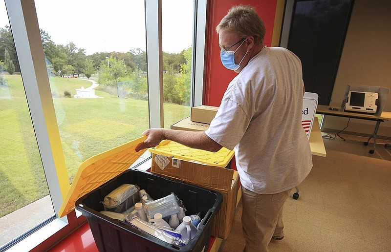 Election equipment specialist Bart Moreland checks a container of masks and cleaners Thursday at the Hillary Rodham Clinton Children’s Library and Learning Center in Little Rock while setting up the site for early voting.
(Arkansas Democrat-Gazette/Staton Breidenthal)