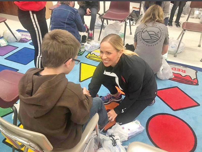 Courtney North smiles as she helps one student try on a pair of shoes at last year’s Shoe Project. North’s mom, Peggy Clark, helped start The Shoe Project almost 30 years ago with her Sunday School class.