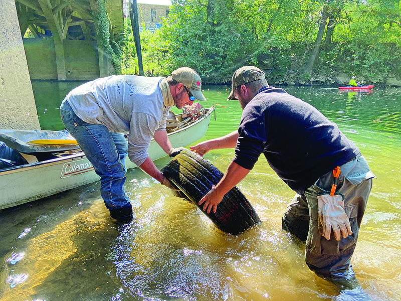 Nick Spivey, left, and Nathan Huffman pull out a tire from the Poke Bayou in Batesville during a cleanup Oct. 3.