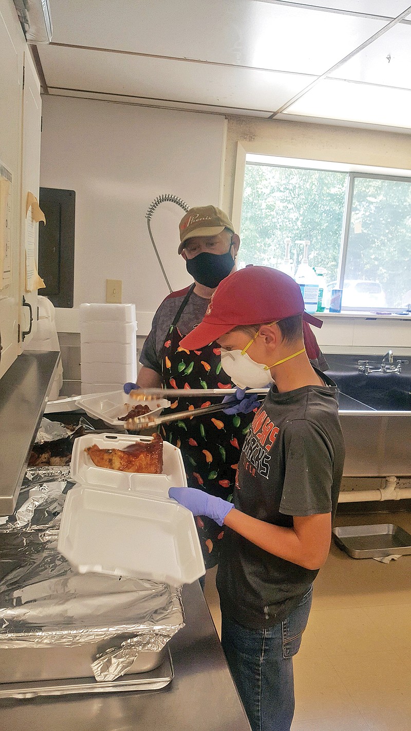 Fred Belli, a volunteer with Breakin’ Bread Ministries in Heber Springs, watches as Henry Lewis prepares one of the to-go meals that are provided to those in need.