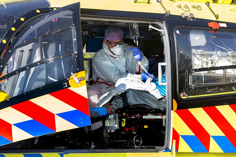 A covid-19 patient is being tended to prior to being airlifted with the helicopter from FlevoZiekenhuis, or FlevoHospital, in Almere, Netherlands, Friday, Oct. 23, 2020. In the latest sign of the scale of the coronavirus pandemic sweeping across Europe, a helicopter started airlifting covid-19 patients from the Netherlands to an intensive care unit in the German city of Muenster. (AP Photo/Peter Dejong)

