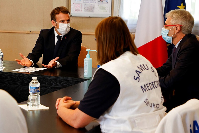 French President Emmanuel Macron (left) chairs a meeting with the medical staff of the Rene Dubos hospital center in Pontoise, outside Paris, on Friday, Oct. 23, 2020. A curfew that has been imposed in eight regions of France, including Paris and its suburbs, is being extended to 38 more regions and Polynesia as France copes with a spike in coronavirus cases.