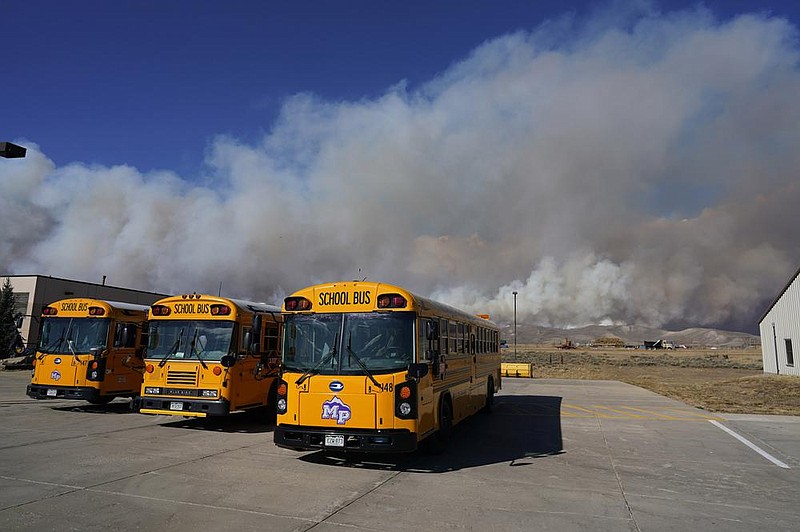 Buses sit idle Thursday at a high school in Granby, Colo., as smoke from a wildfire rises from nearby mountain ridges.
(AP/David Zalubowski)