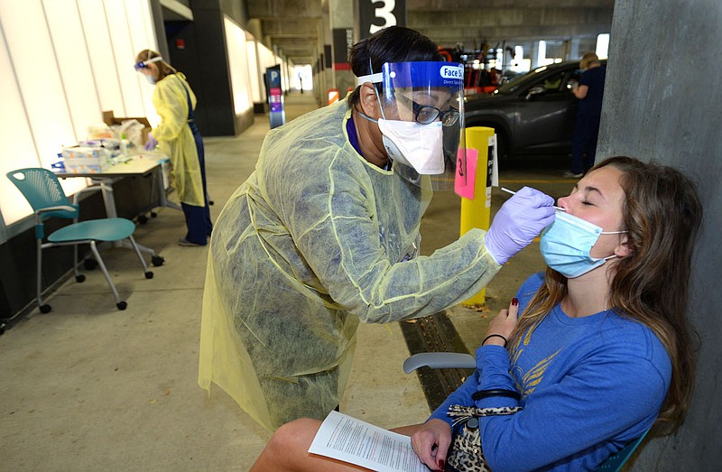 Riley Hunt, a University of Arkansas freshman from Greenville, Ohio, gets a coronavirus test Friday, Oct. 23, 2020, from Erica Nash, a licensed practical nurse with Arkansas Foundation of Medical Care and the state Department of Health inside the Garland Avenue parking garage on the Fayetteville campus. (NWA Democrat-Gazette/Andy Shupe)