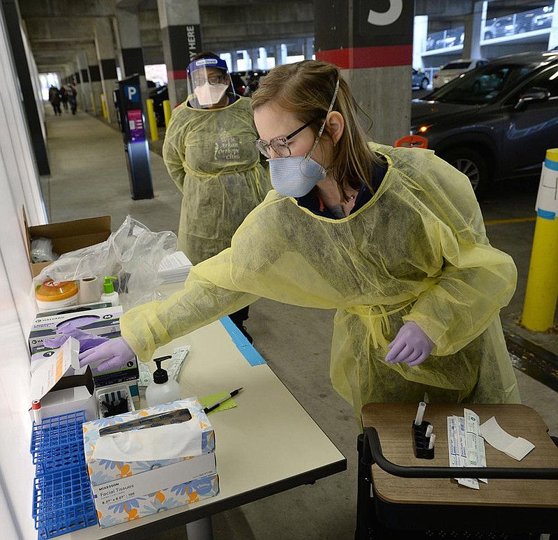 Roxana Hutchcroft, a nurse with Arkansas Foundation of Medical Care and the state Health Department, collects supplies Friday before administering a covid-19 test Friday at the new testing site inside the Garland Avenue parking garage on the University of Arkansas campus in Fayetteville. (NWA Democrat-Gazette/Andy Shupe)