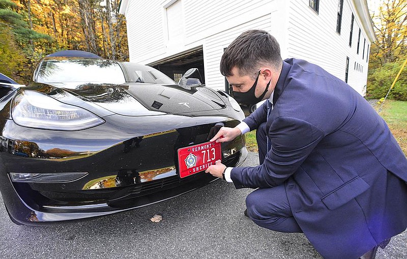 Windham County, Vt., Sheriff Mark Anderson puts  the license plate on a Tesla that will be converted  into a police vehicle as the department tests the viability of electric patrol cars.
(The Brattleboro Reformer/Kristopher Radder)