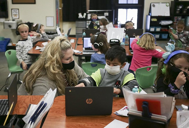 Kindergarten teacher Kim Crawford helps Ian Lopez with an assignment earlier this month at Clinton Elementary School in Clinton. Teachers are putting in longer hours and dealing with daily frustrations that have some thinking about quitting. More photos at arkansasonline.com/1025covidclass/.
(NWA Democrat-Gazette/Charlie Kaijo)