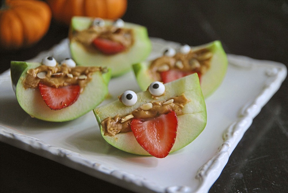 Turn apple wedges into spooky, silly and healthful apple monsters with almond teeth and sliced strawberry eyes. (TNS/Pittsburgh Post-Gazette/Gretchen McKay)
