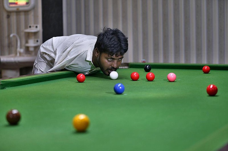 Mohammad Ikram plays snooker with his chin at a local snooker club in Pakistan. Ikram, 32, was born without arms, but his physical disability doesn’t get in the way of playing the game. (AP/Anjum Naveed) 