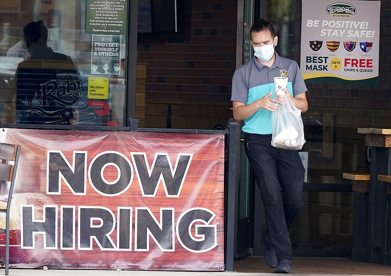 FILE - In this Sept. 2, 2020 file photo, a customer wears a face mask as they carry their order past a now hiring sign at an eatery in Richardson, Texas. The number of Americans seeking unemployment benefits fell last week to 751,000, the lowest since March, but it's still historically high and indicates the viral pandemic is still forcing many employers to cut jobs.