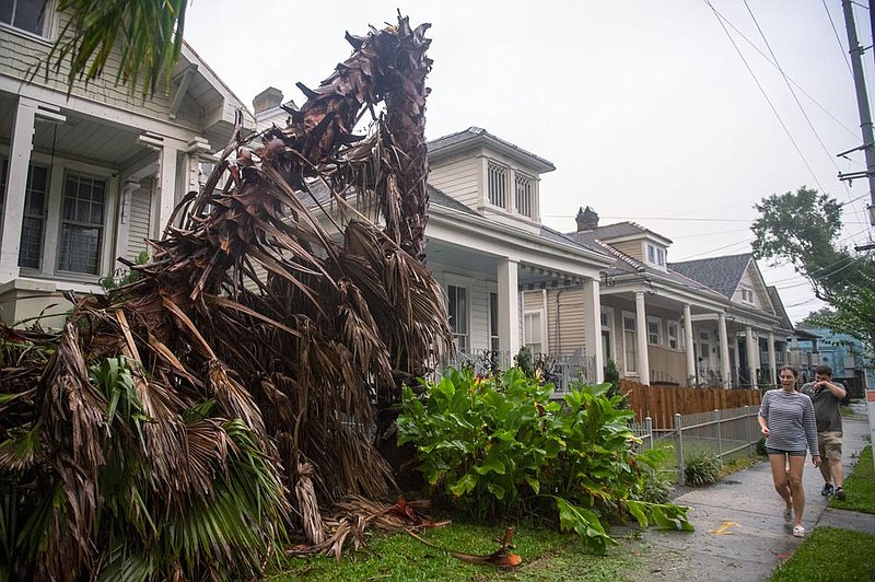 People walk past a downed tree in New Orleans as the outer eye wall of Hurricane Zeta passes through Wednesday evening.
(AP/The Times-Picayune/The New Orleans Advocate/Chris Granger)