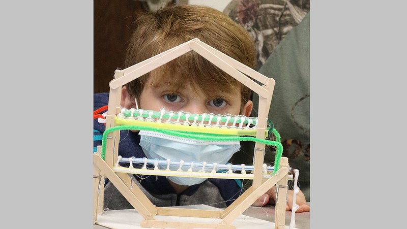 Evan Myers looks through his winning entry in October’s Second Saturday Family FunDay contest at the Arts & Science Center for Southeast Arkansas in Pine Bluff. Contestants were tasked to engineer a bone bridge with on-hand supplies.