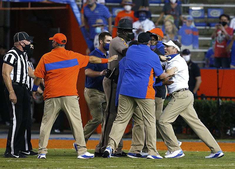 Florida coach Dan Mullen, right, is held back by coaches and law enforcement after a fight broke out at the end of the first half of the team’s NCAA college football game against Missouri in Gainesville, Fla., Saturday.