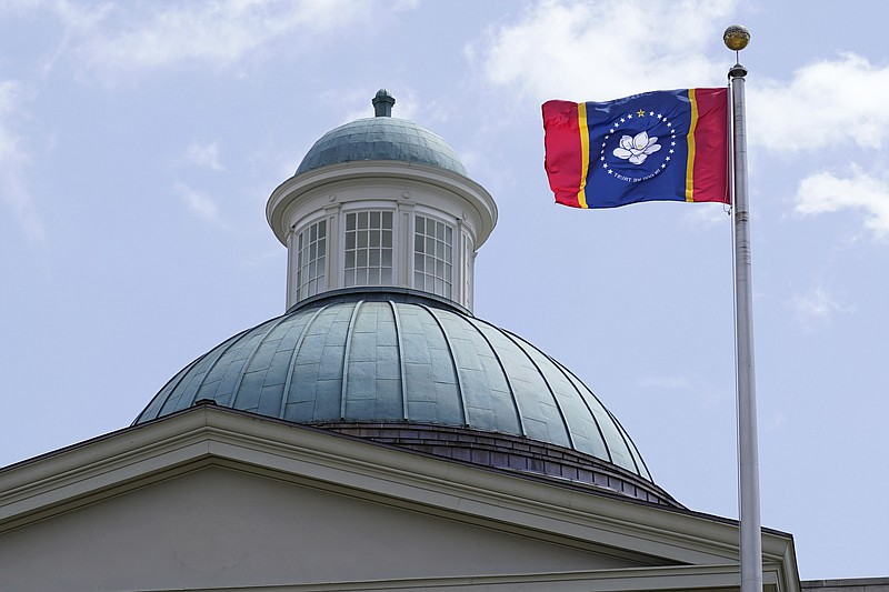 The magnolia flower centered banner chosen Wednesday, Sept. 2, 2020 by the Mississippi State Flag Commission flies outside the Old State Capitol Museum in downtown Jackson, Miss. The nine member committee voted to recommend a design with the state flower, now known as the "In God We Trust," flag. That design will go on the November ballot for voters consideration and if approved, it will become the new state flag. (AP Photo/Rogelio V. Solis)