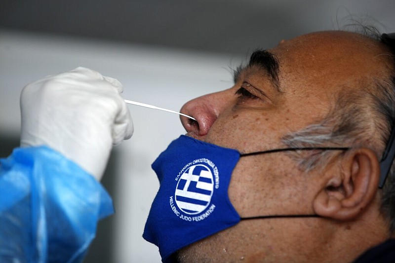 A medical staff member from the National Health Organization conducts a rapid covid test on a man, wearing a face mask with the Greek flag, in Athens, Thursday, Nov. 5, 2020. 