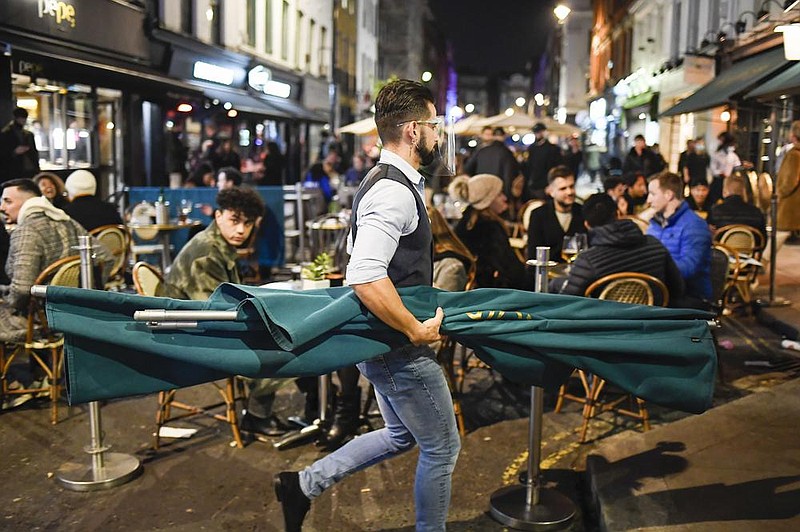 As customers have a final pint or two Wednesday at a pub in London’s Soho area, a waiter gets ready for today’s lockdown.
(AP/Alberto Pezzali)