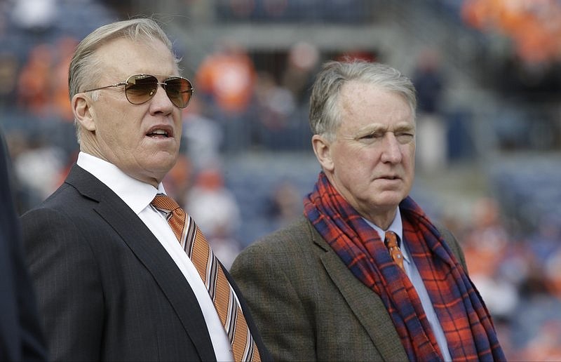 In this Jan. 1, 2017, file photo, Denver Broncos general manager John Elway, left, stands with Broncos President and CEO Joe Ellis before an NFL football game against the Oakland Raiders in Denver. Both have tested positive for COVID-19.