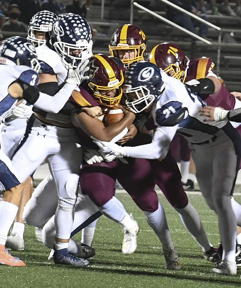 The Greenwood defense gang-tackles Lake Hamilton running back Tevin Woodley on Friday during the Bulldogs’ 38-28 victory over the Wolves in Pearcy.
(The Sentinel-Record/Grace Brown)