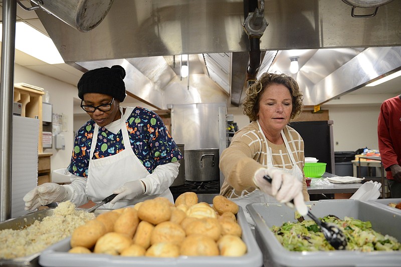 File Photo: Elizabeth Gilbert (left) and Marie Tosh prepare food plates at the Stewpot ahead of large serving at First United Methodist Church in Magnolia. Not pictured is George Gilbert.