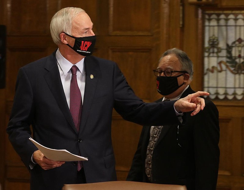 Gov. Asa Hutchinson (left) enters the room with Secretary of Health Dr. Jose Romero (right) before the weekly covid-19 press briefing on Tuesday, Nov. 10, 2020, at the state Capitol in Little Rock. 
(Arkansas Democrat-Gazette/Thomas Metthe)