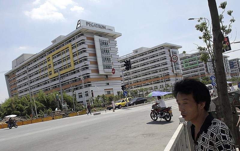 People walk near several buildings of a Pegatron factory in Shanghai, China, Tuesday, July 30, 2013. A labor rights group has accused Pegatron, a supplier of Apple Inc. in China of misconduct including withholding employees' pay and environmental violations. The report Monday by China Labor Watch said it found violations of the law and of Apple's pledges about working conditions at facilities operated by Pegatron Corp., a Taiwanese company.