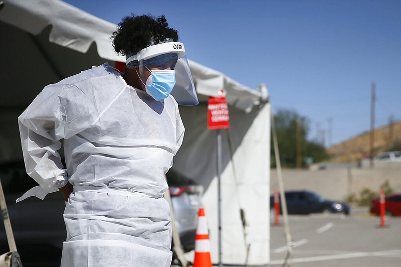 FILE - In this Oct. 26,2020, file photo, a medical worker stands at a covid-19 state drive-thru testing site at UTEP, in El Paso, Texas.