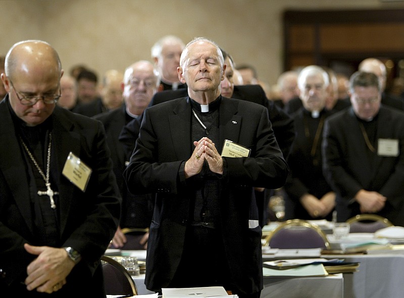FILE - In this Nov. 10, 2003 file photo, Cardinal Theodore Edgar McCarrick, Archbishop of Washington, D.C., center, joins fellow clergy in prayer at the end of the opening session of the U.S. Conference of Catholic Bishops meeting in Washington. McCarrick – who was defrocked by Pope Francis in 2019 – served as head of Catholic dioceses in Metuchen and Newark, New Jersey, and in Washington. A report released by the Vatican on Monday, Nov. 9, 2020, found that three decades of bishops, cardinals and popes dismissed or downplayed reports of McCarrick’s misconduct with young men. (AP Photo/J. Scott Applewhite, File) story.lead_photo.caption