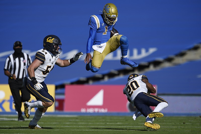 UCLA quarterback Dorian Thompson-Robinson, center, leaps over California cornerback Josh Drayden, right, on a run during the first half of Sunday’s game as Evan Tattersall looks on in Los Angeles. - Photo by Kelvin Kuo of The Associated Press story.lead_photo.caption
