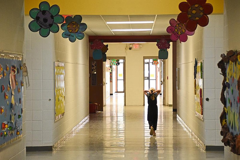 A student secures her mask Thursday while walking down a hallway at her school in Smackover. Students and staff members have learned to keep their distance, to pass without touching.
(Arkansas Democrat-Gazette/Staci Vandagriff)